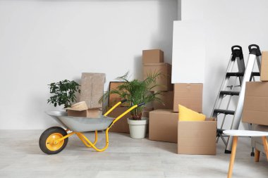 Merdiveni olan el arabası, kutuları taşıyan ve odada boş poster olan.