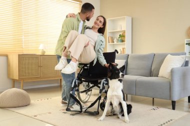 Genç adam evde fiziksel engelli karısına yardım ediyor.