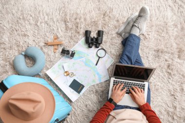 Haritası, dizüstü bilgisayarı ve bavulu olan genç bir turist eve dönüş yolculuğunu planlıyor. Güzergah kavramı