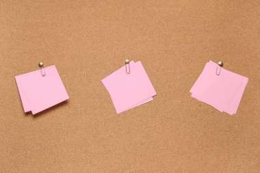 Arkaplan olarak mantar tahtasında ataç olan boş yapışkan notlar