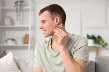 Genç adam evde pamuklu tomurcuklarla kulakları temizliyor.