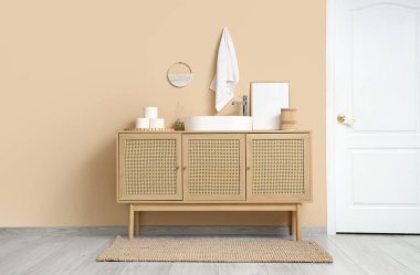 Lavabosu, ahşap dolabı ve beyaz kapısı olan şık bir banyo.