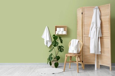 Sandalyesi, katlanır perdesi ve rafında tuvalet kağıdı olan şık bir tuvalet.