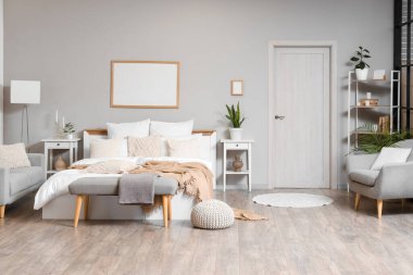 Şık bir yatak odası, rahat bir yatak odası, koltuk ve beyaz bir kapı.