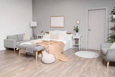 Şık bir yatak odası, rahat bir yatak, kanepe ve beyaz bir kapı.