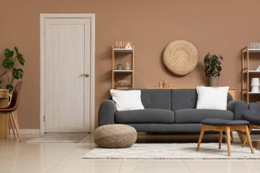 Gri kanepe, hasır puf ve beyaz kapılı şık bir oturma odası.