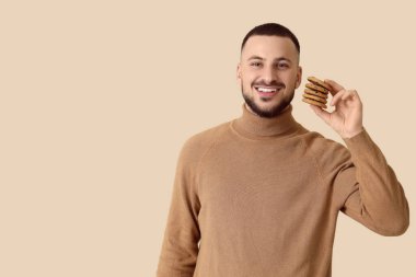 Bej arka planda kurabiyeleri olan genç bir adam.