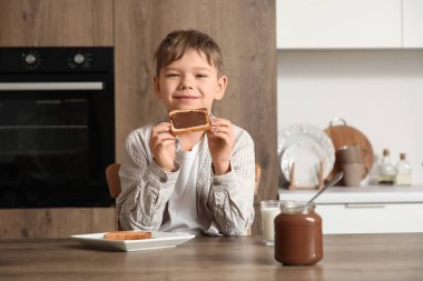 Mutfakta çikolata ezmeli tost yiyen tatlı küçük çocuk.