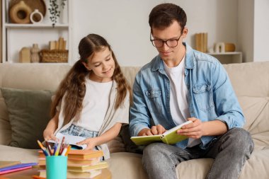 Evdeki kanepede ders kitabı okuyan genç bir kız.