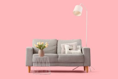 Şık gri kanepe ve pembe arka planda lale çiçekleri olan kahve masası.