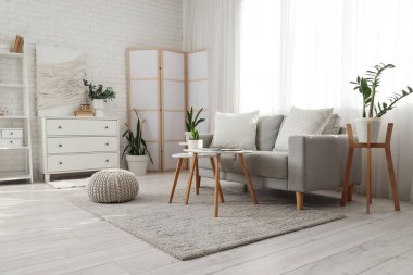 Perde, kanepe ve bitkilerle aydınlık oturma odasının içinde.