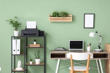 Modern yazıcı, dizüstü bilgisayar ve masa lambası olan bir işyeri.