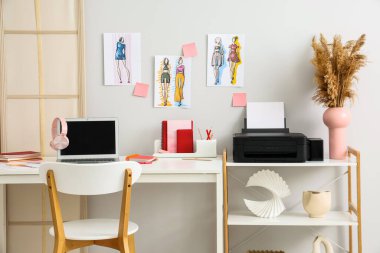 Modern yazıcı ve dizüstü bilgisayarlı giyim tasarımcısının işyeri