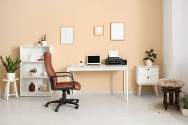 Modern yazıcısı, dizüstü bilgisayarı ve şık ev ofisinde rahat koltuğu olan işyeri