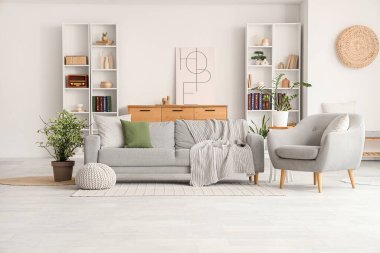 Gri kanepesi, koltuğu ve raf ünitesi olan şık bir oturma odası.