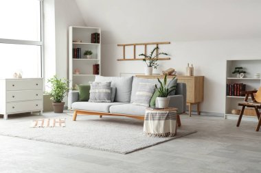 Gri kanepesi, çiçekleri ve raf ünitesi olan şık bir oturma odası.