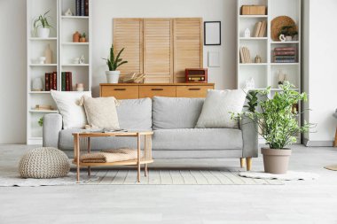 Gri kanepesi, sehpası ve raf ünitesi olan şık bir oturma odası.