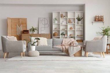 Gri kanepesi, koltuğu ve raf ünitesi olan şık bir oturma odası.