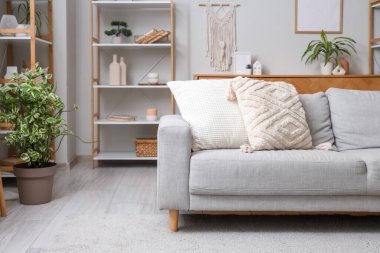 Gri kanepesi, çiçekleri ve raf üniteleri olan şık bir oturma odası.