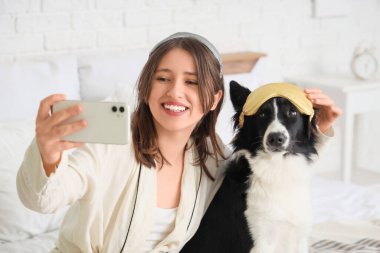 Güzel genç bir kadın ve evde selfie çeken uyku maskeli şirin bir Border Collie köpeği.