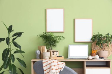 Rahat çalışma alanı, modern dizüstü bilgisayarı ve ev bitkileri olan şık bir ofis.