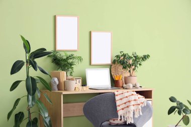 Rahat çalışma alanı, modern dizüstü bilgisayarı ve ev bitkileri olan şık bir ofis.