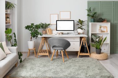 Rahat çalışma alanı, modern bilgisayar ve ev bitkilerine sahip şık bir ofis.