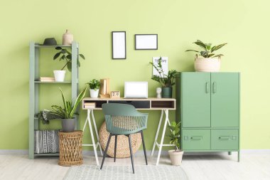 Rahat çalışma alanı, kabine, modern dizüstü bilgisayar ve ev bitkilerine sahip şık bir ofis.