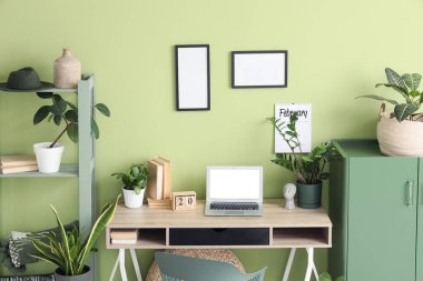 Rahat çalışma alanı, kabine, modern dizüstü bilgisayar ve ev bitkilerine sahip şık bir ofis.