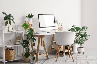 Rahat çalışma alanı, modern bilgisayar ve ev bitkilerine sahip şık bir ofis.