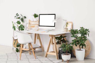 Rahat çalışma alanı, modern bilgisayar ve ev bitkilerine sahip şık bir ofis.