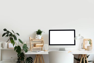 Rahat çalışma alanı, modern bilgisayar ve ev bitkilerine sahip şık bir ofis.