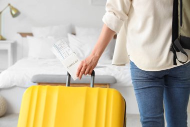 Otel odasında pasaport ve bavulu olan kadın turist.