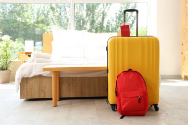 İçinde pasaport ve sırt çantası olan bavul otel odasının içinde.