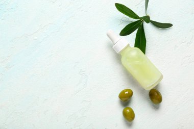 Bir şişe doğal yağ, yeşil zeytin ve hafif arkaplanda dal