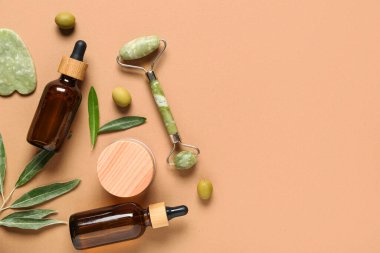 Doğal kozmetik ürünleri, yüz masajı araçları ve arka planda yeşil zeytinli kompozisyon