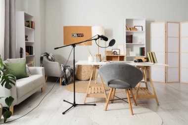 Podcaster 'ın atölyesinin içinde iş yeri, kanepe ve kitaplıklar var.
