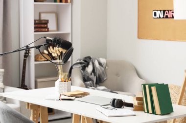 Podcaster 'ın atölyesinde dizüstü bilgisayarı ve kitapları olan işyeri.