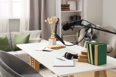 Podcaster 'ın atölyesinde dizüstü bilgisayarı ve kitapları olan işyeri.