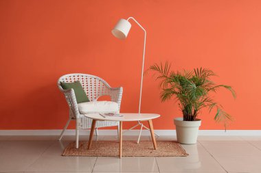 Koltuğu, masası ve palmiyesi olan şık bir oturma odası.