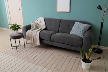 İçinde siyah kanepe, masa ve bitkiler olan şık bir oturma odası.