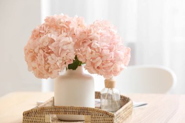 Yemek masasında pembe ortanca çiçekli tepsi ve sazlık ayırıcı, yakın plan.