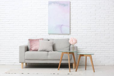 Oturma odasındaki kanepenin yanındaki masada pembe ortanca çiçekli vazo.