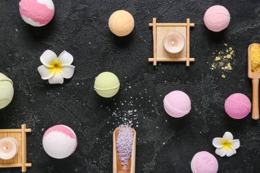 Deniz tuzu, çiçek ve koyu arkaplanda yanan mumlarla banyo bombaları.