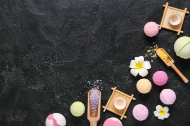 Deniz tuzu, çiçek ve koyu arkaplanda yanan mumlarla banyo bombaları.