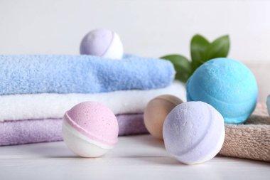 Banyo bombaları beyaz ahşap masada havlular, yakın plan.