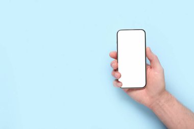 Mavi arka planda boş cep telefonu olan bir erkek. Tıp konsepti