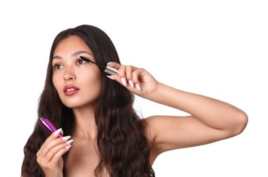 Güzel bir Asyalı kadın beyaz arka plana rimel sürüyor.