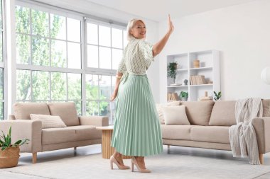 Güzel olgun kadın evde dans ediyor.