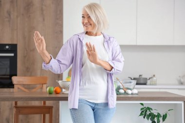 Mutfakta dans eden olgun bir kadın.